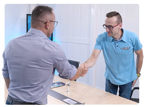 Two business professionals shaking hands across a desk, symbolizing a successful partnership meeting in a modern office setting.