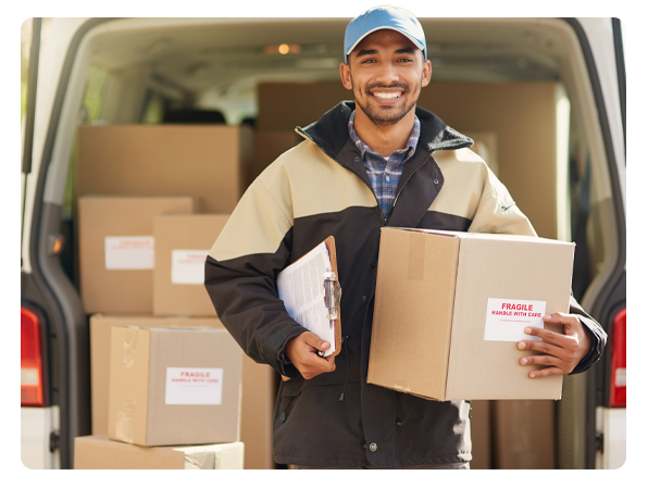 Delivery driver holding a package in front of a van loaded with cardboard boxes.