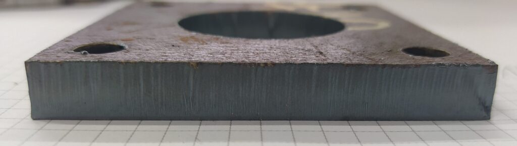 Przekrój ciętej laserowo stali – widoczne gładkie lico oraz charakterystyczna chropowata krawędź górna po procesie cięcia.