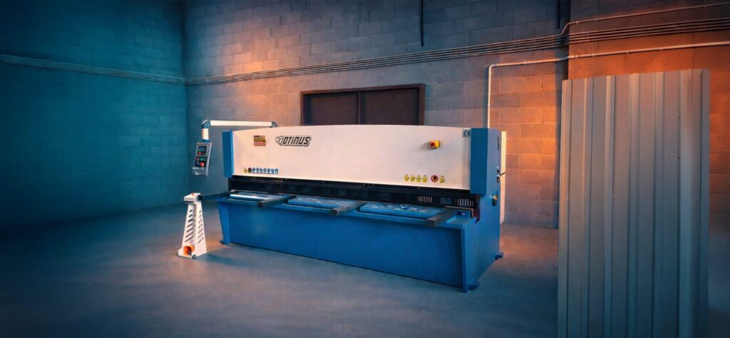 Otinus Base guillotine shear in a modern production hall, highlighting its heavy-duty construction, intuitive control panel, and stable working table designed for precise sheet metal cutting.