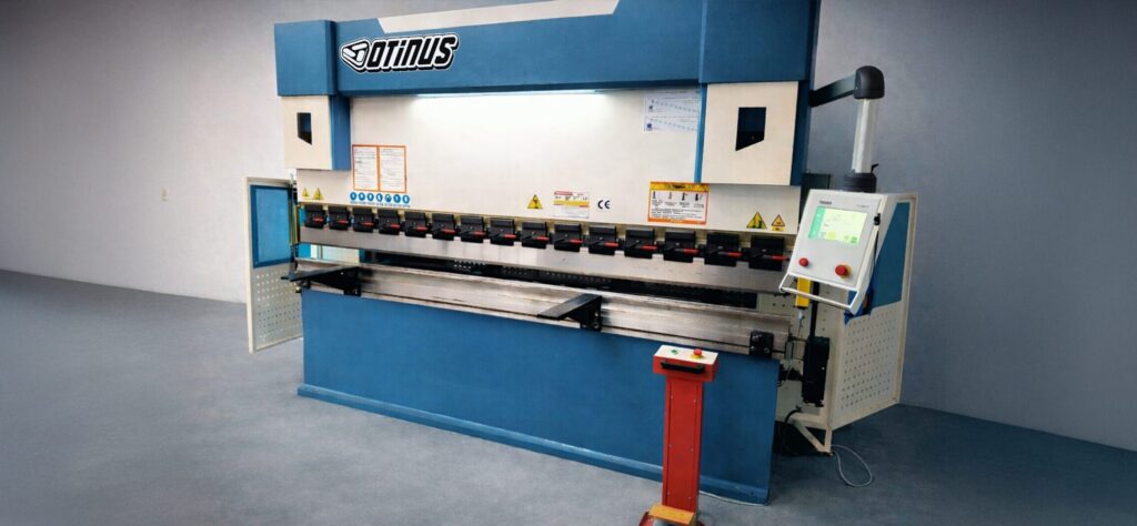 Otinus press brake with the Delem DA-58T control system and CNC panel, enabling precise sheet metal bending while maintaining high safety standards in a modern industrial hall.