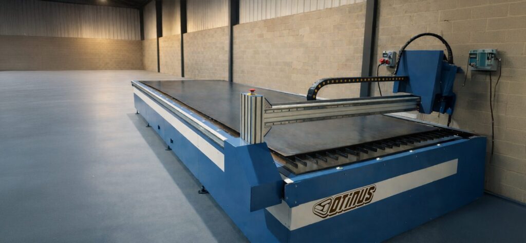 Otinus 6020-D plasma cutting machine with a water table, side view highlighting the stable structure and gantry guideways in a spacious industrial hall.