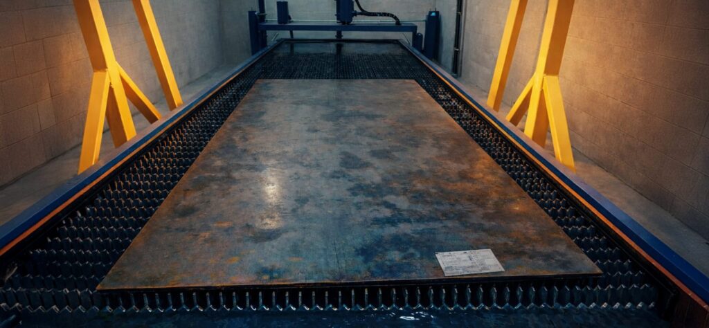 A CNC plasma cutting machine with an oxy-fuel torch and a water table, designed for precise cutting of thick steel plates in industrial environments.