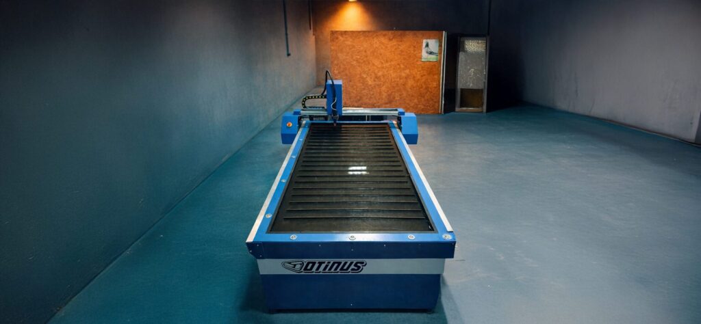 Industrial Otinus plasma cutting machine with a water table, presented frontally in a production hall, designed for precise and high-efficiency metal cutting.