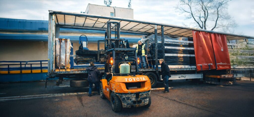Unloading industrial machines from a semi-trailer using a forklift, illustrating an efficient and safe industrial logistics process at the facility.